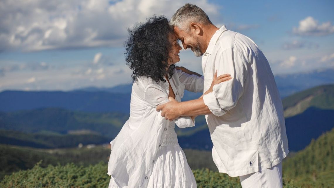 Smiling couple embracing in a picturesque mountain setting, capturing a joyful moment together.