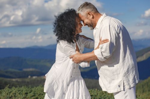 Smiling couple embracing in a picturesque mountain setting, capturing a joyful moment together.